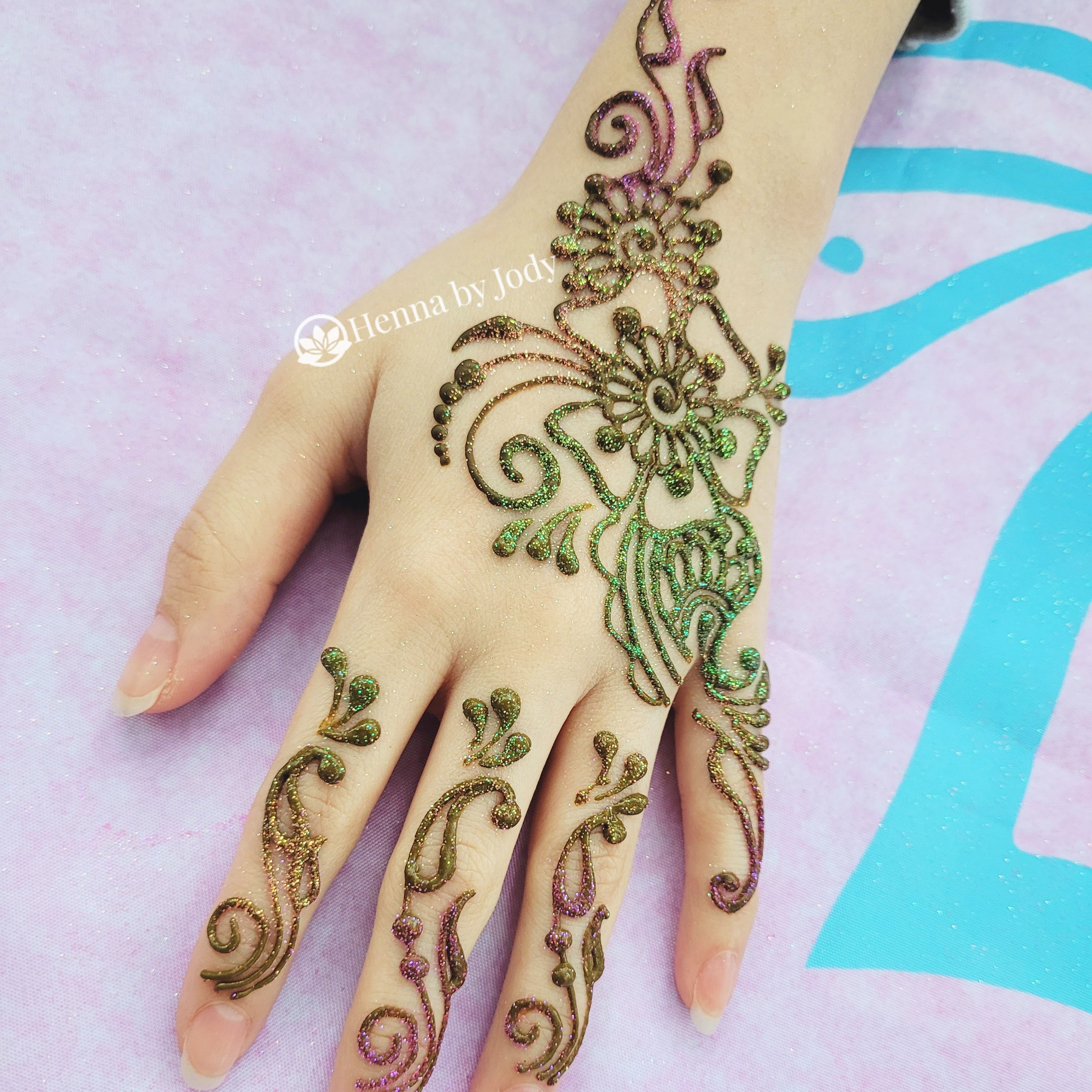 UV or black light reflective glow glitter on a henna design on a hand.