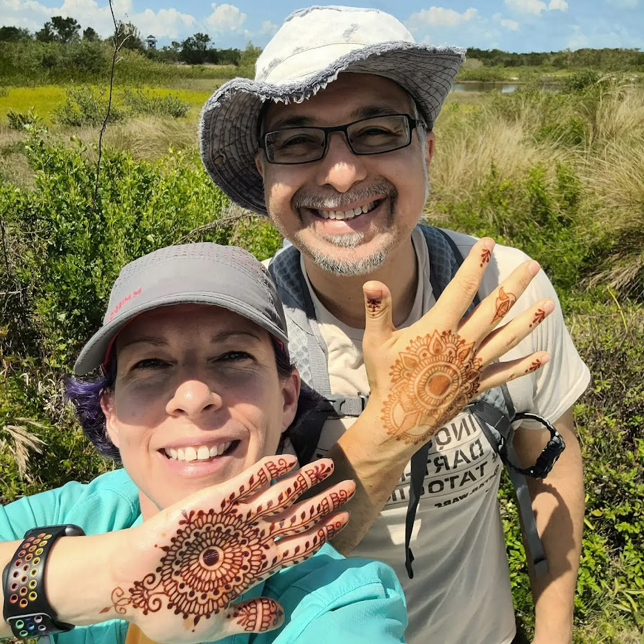 Selfie of Jody and Asad on a hike holding up hennaed hands