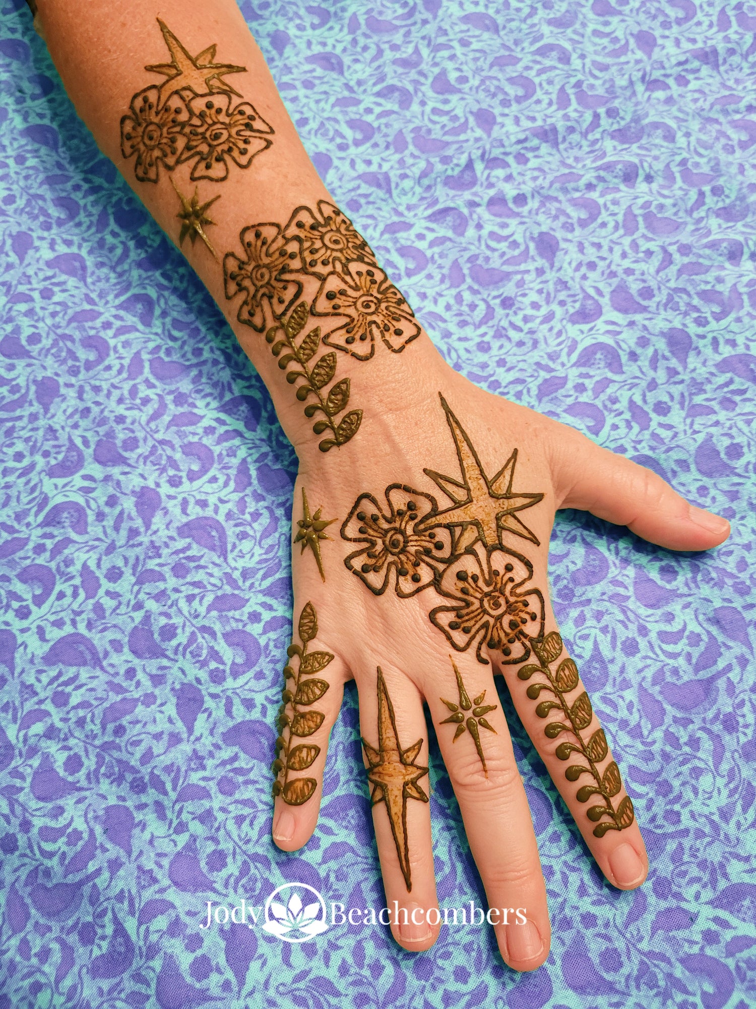 Mid century modern henna design with retro flowers and starbursts on the hand and arm