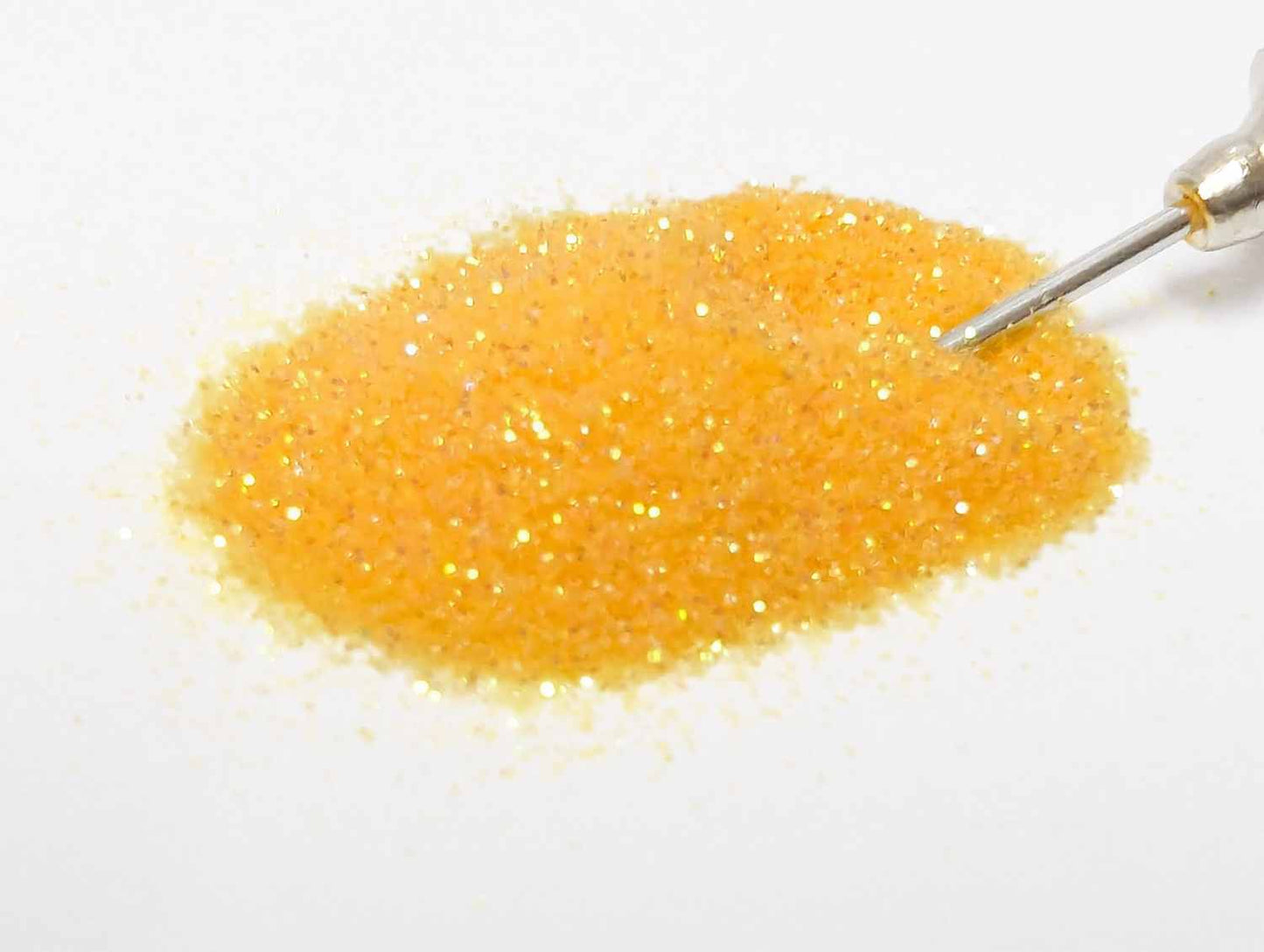 A small pile of UV orange creamsicle body glitter with the tip of an applicator in the glitter
