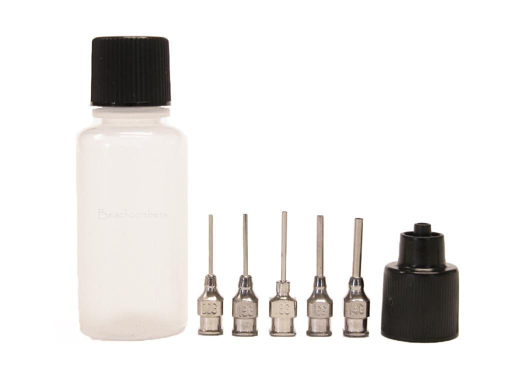 An empty applicator bottle with 5 syringe tips and a couple beside it for applying henna or glue