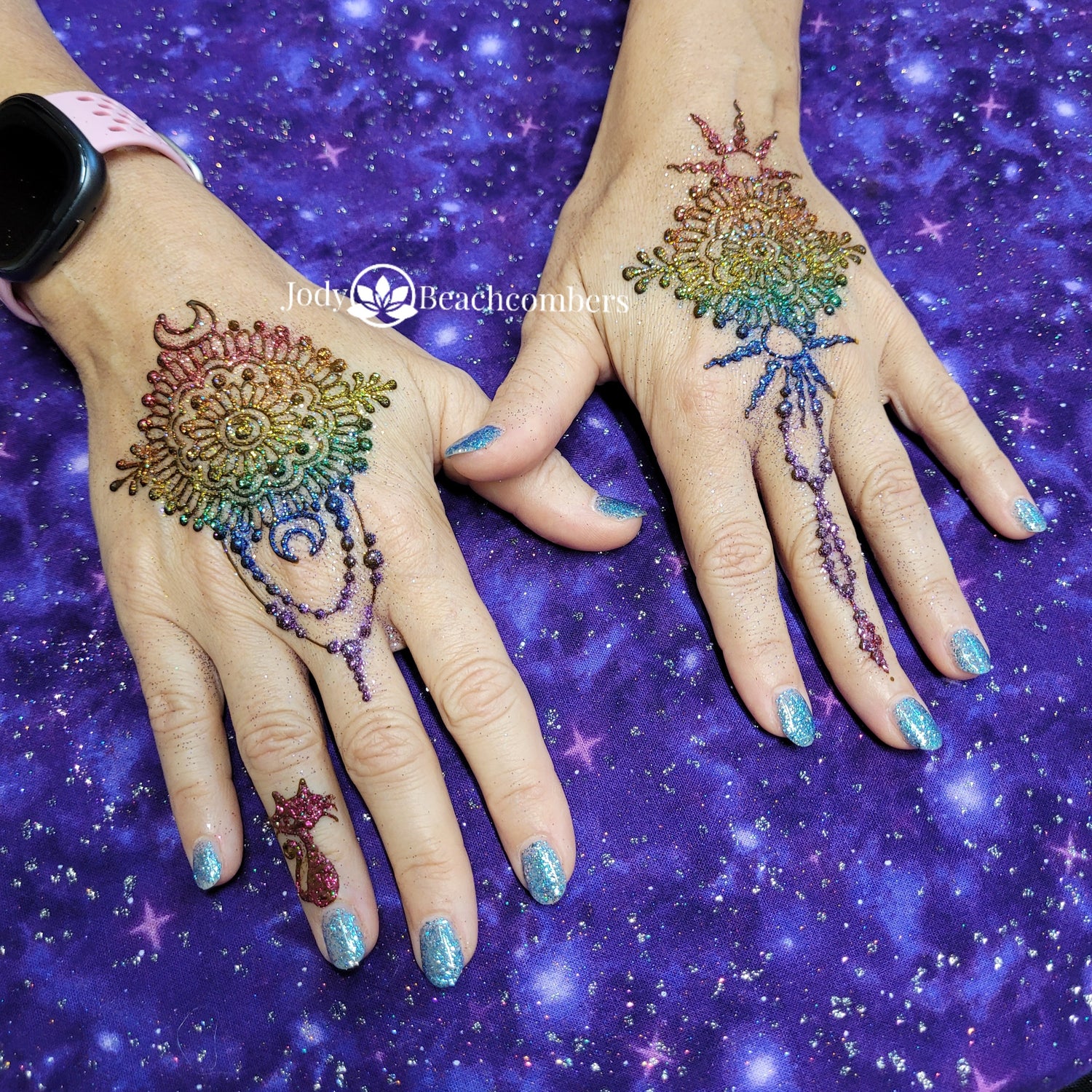 Rainbow glitter on henna designs on two hands.