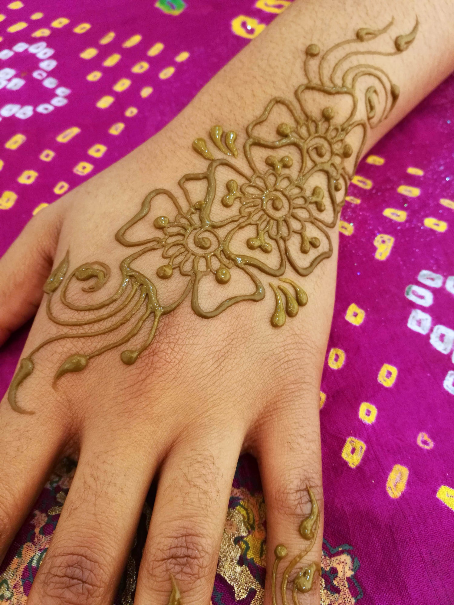 Fresh juicy henna lines in a 3 flower group on the top of a hand.