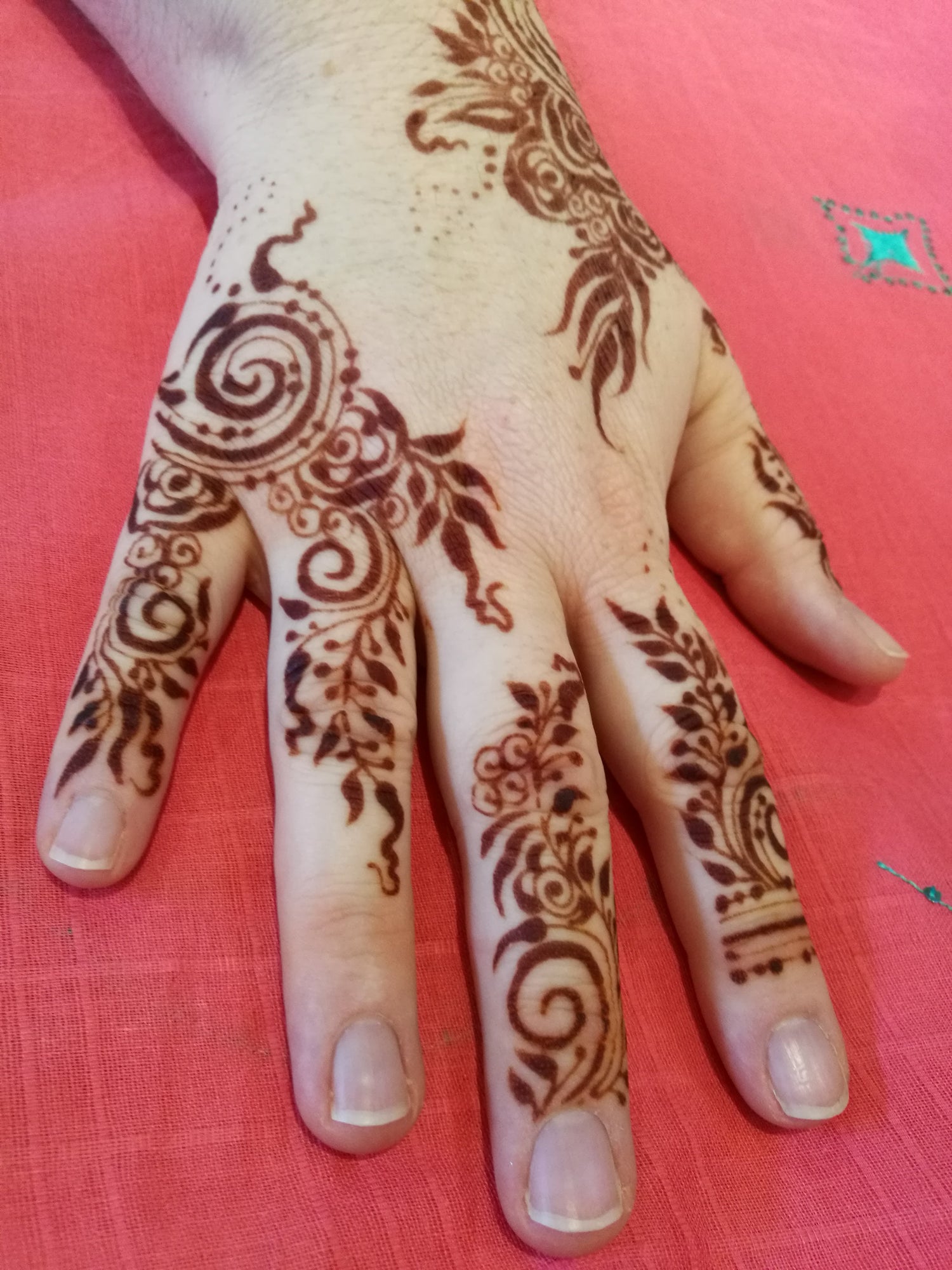 Top of a white hand with a lovely gulf style henna design. Stain is at full color.