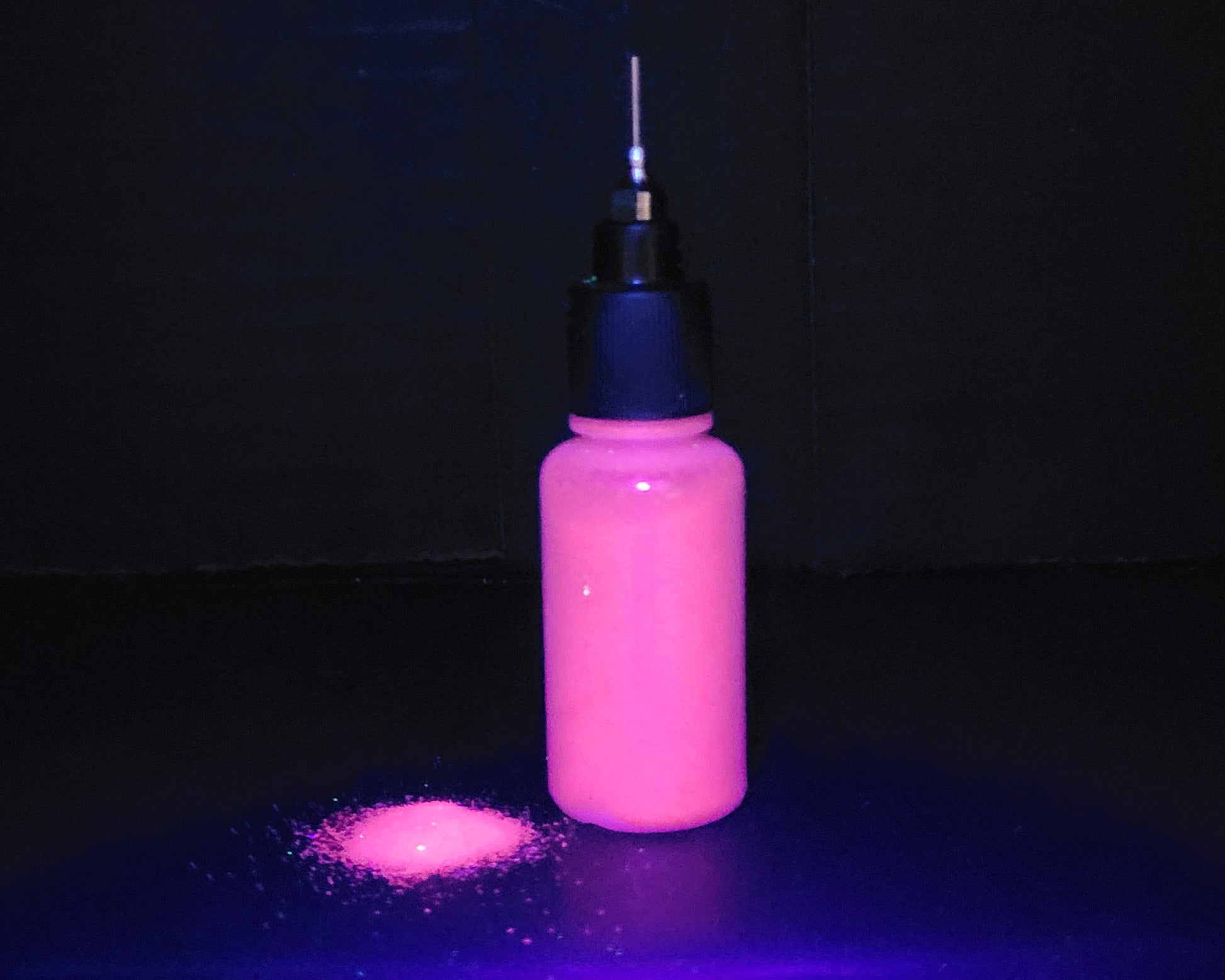 bottle of UV glitter glowing in UV light