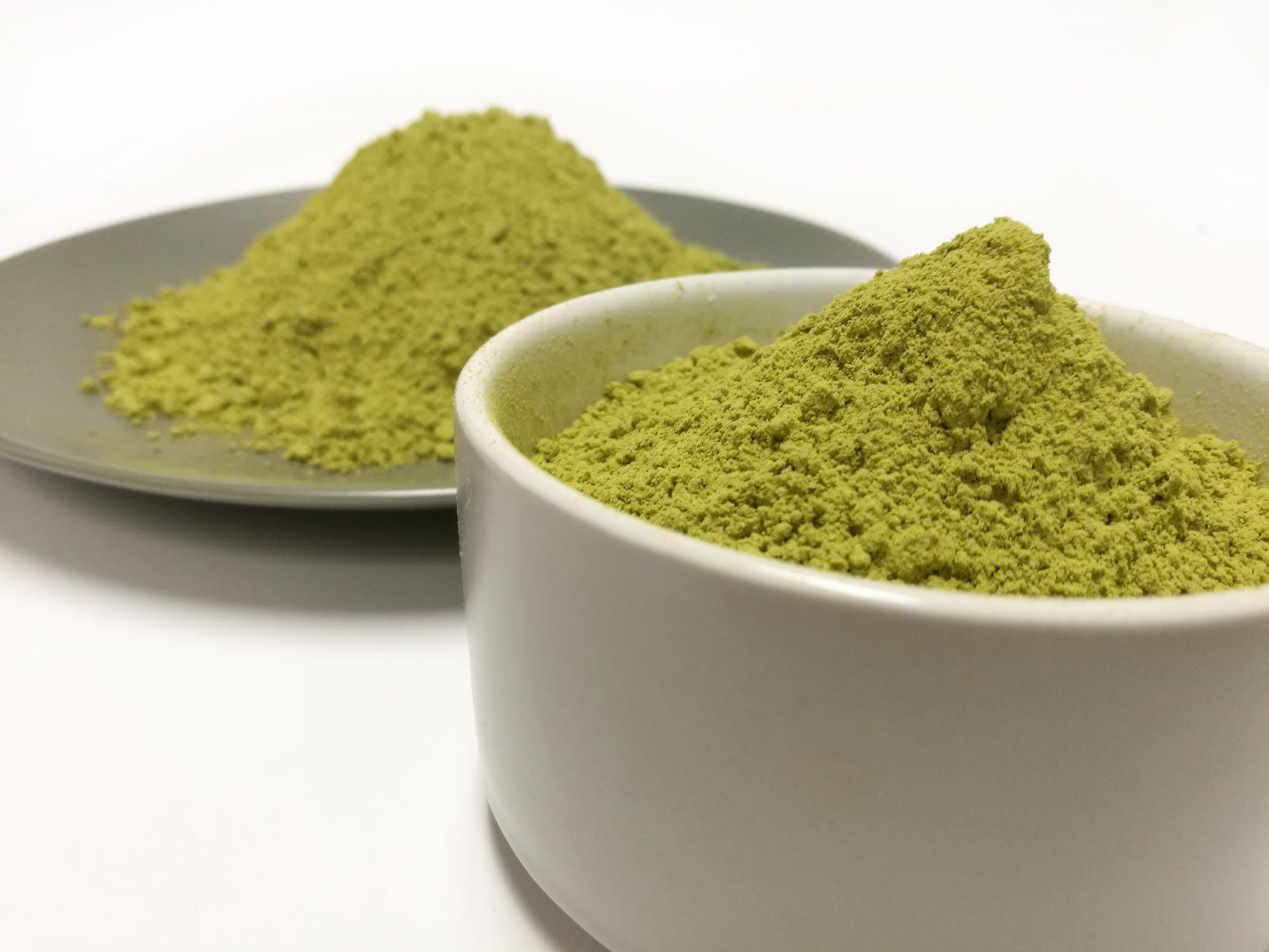 Loose ORa henna powder in a small container and on a small plate.