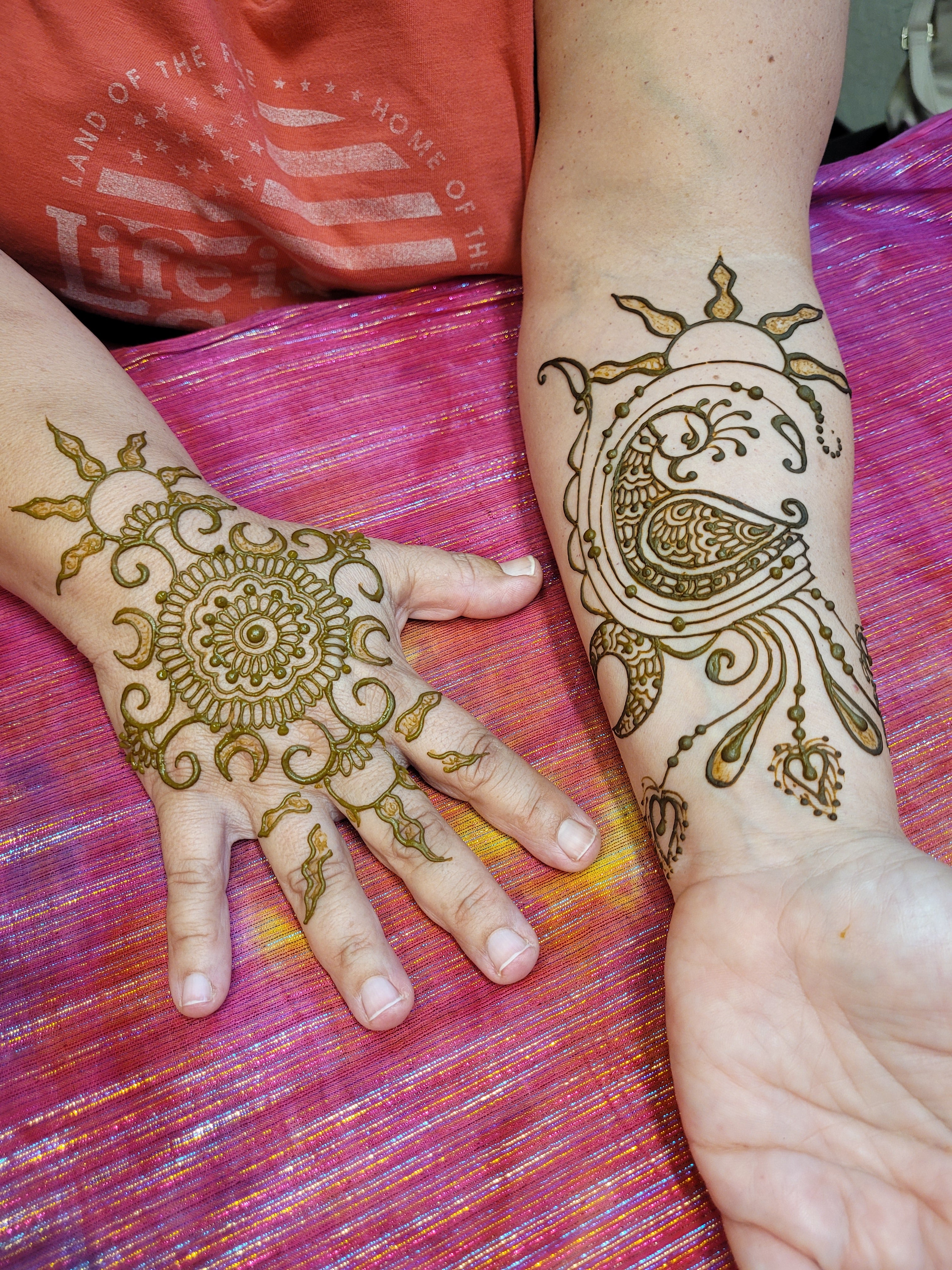 MAndala with sun and moon on the hand and a peacock with a sun and moon on the forearm