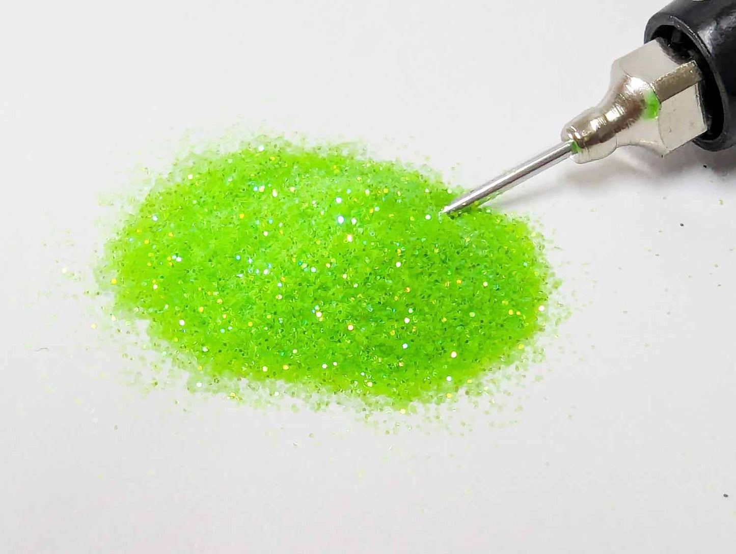 Small pile of UV electric kiwi green body glitter with applicator tip in the glitter