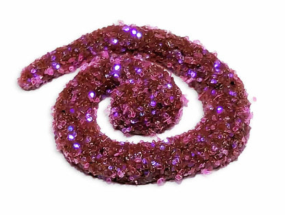 A spiral of wet henna covered in UV cosmic berry pink body glitter