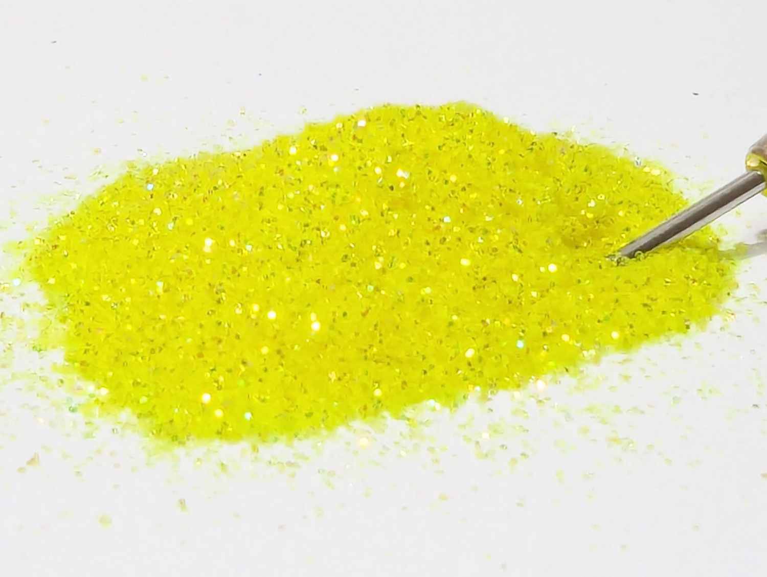 A small pile of UV yellow neon lemonade body glitter with an applicator tip in teh glitter